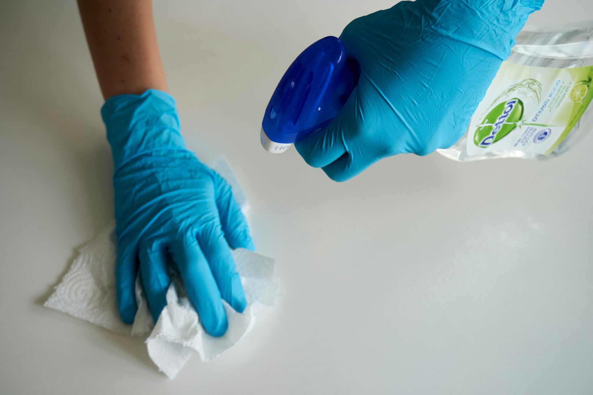Persona con guantes azules sosteniendo textil blanco.